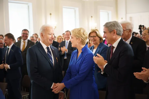 Biden schüttel Schwesig die Hand in einem Pulk aus Leuten.