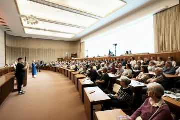 Ein Plenum in einem Saal auf der rechten Seite. Links gegenüber stehen mehrere Menschen. In der Mitte Manuela Schwesig in einem blauen Kleid. 