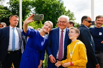 Manuela Schwesig hält ein handy für ein Selfie in die Luft. Rechts neben ihr stehen Steinmeier und ein Junge. 