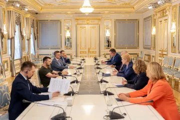 8 Menschen sitzen sich an einem langen Konferenztisch gegenüber.