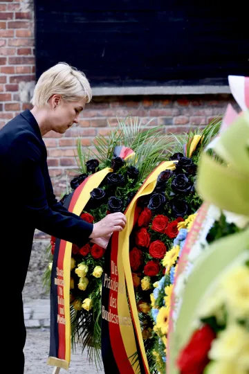 Manuela Schwesig berührt einen Gedenkkranz mit deutscher Flagge.