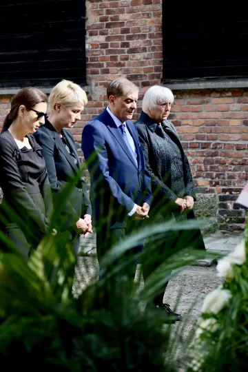 Manuela Schwesig steht mit drei anderen Personen auf einem Platz. Sie falten die Hände und senken den Blick.