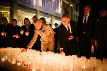 Manuela Schwesig zündet am Abend eine Kerze an. Vor ihr stehen hunderte weiße Kerzen. Im Hintergrund stehen mehrere Menschen. Es ist dunkel.